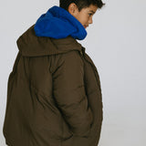 Back and side view of a child wearing a brown puffer jacket over a blue hoodie.